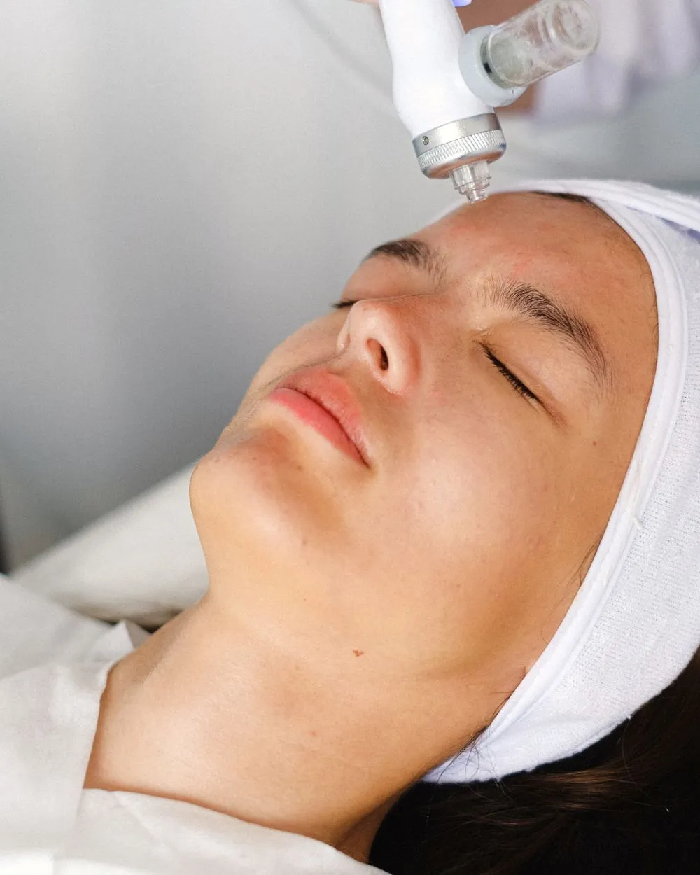Soin hydrafacial en cours sur le front d'une patiente allongée